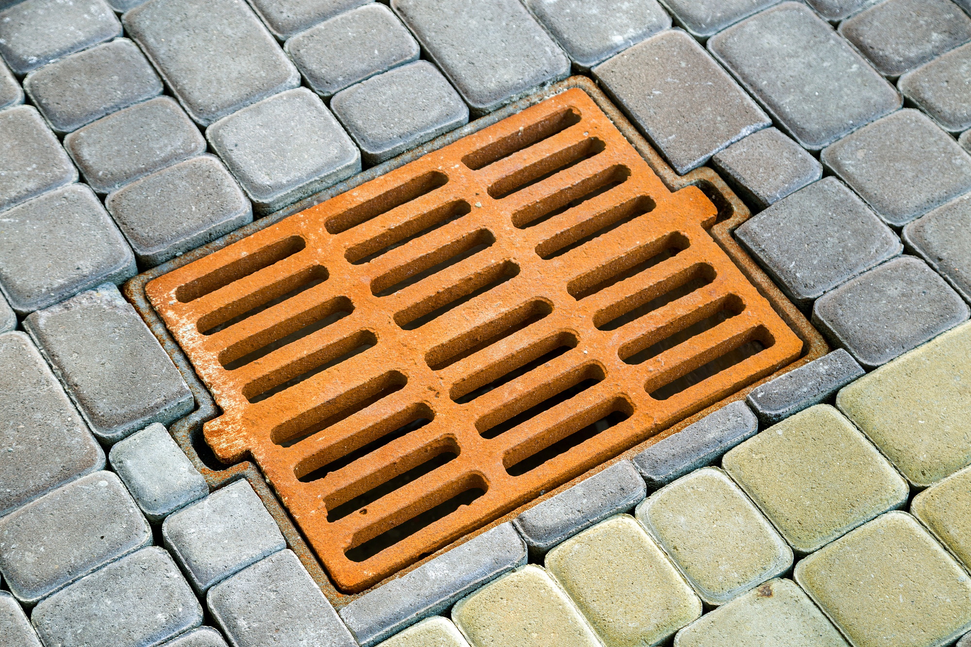Old rusted metal gutter for rain water on the stone paved sidewalk.
